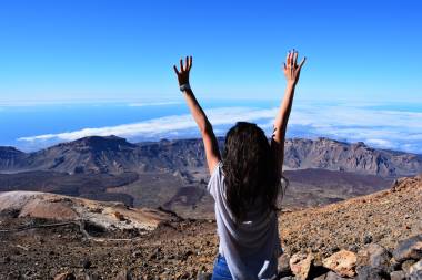 woman-standing-on-mountain-while-raising-her-hands-1053451